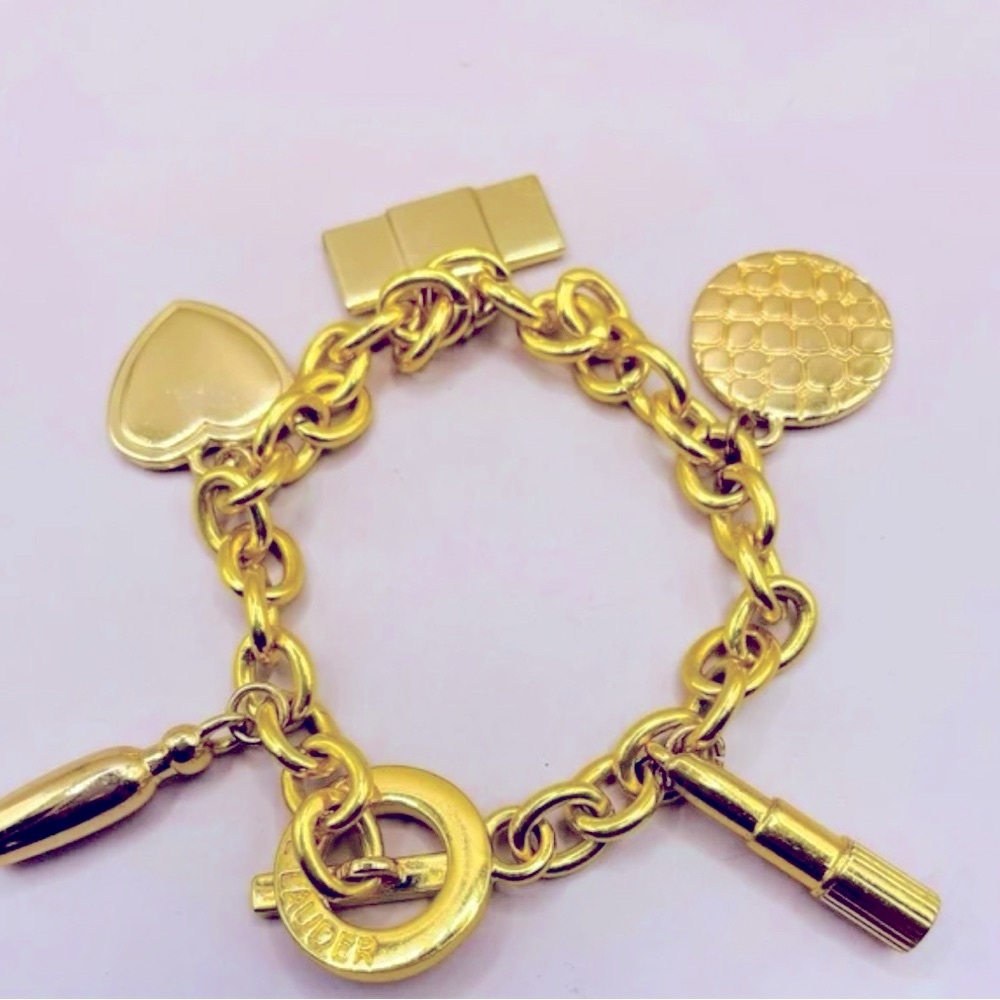 New Estée Lauder Gold Chain Link Design Charm Bracelet with 5 charms and a bag.